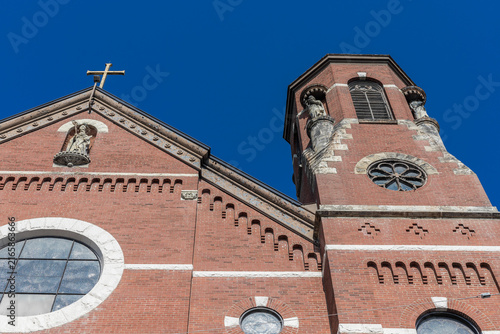 Historic Red Brick Church Facade with Bell Tower Against Blue Sky