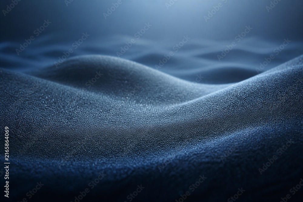 Fototapeta premium Deep blue waves ripple with fine granular texture. Soft light glows from above, casting gentle shadows. The surface shimmers with subtle sparkle and depth. Ideal for serene, abstract