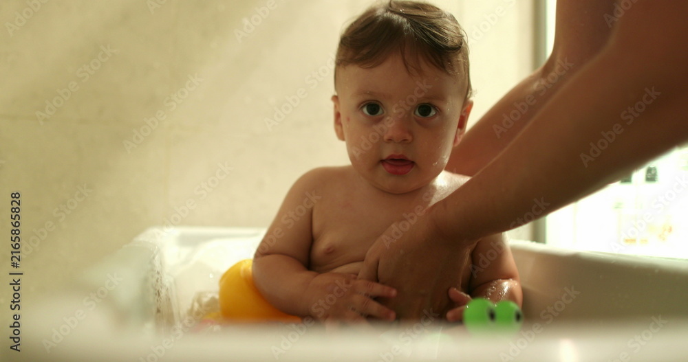 Fototapeta premium Bathing baby infant inside bathtub. Parent washing and cleaning toddler