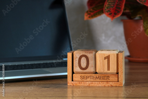 September 1, Knowledge Day. A wooden block calendar, a laptop, and a houseplant on the desk. Back to school.