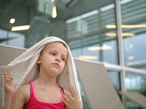 фотографія Girl in a pink swimsuit stands with a white towel draped over her head after swi
