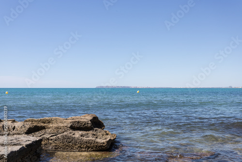 Calm Blue Sea with Rocky Coastline and Yellow Buoys