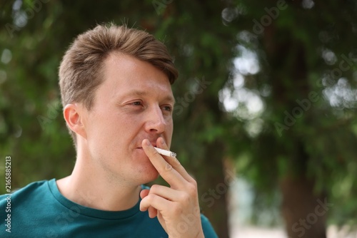 Man smoking cigarette outdoors, space for text