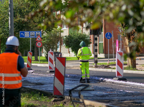 Road construction workers in high-visibility safety gear coordinating urban street pavement repairs