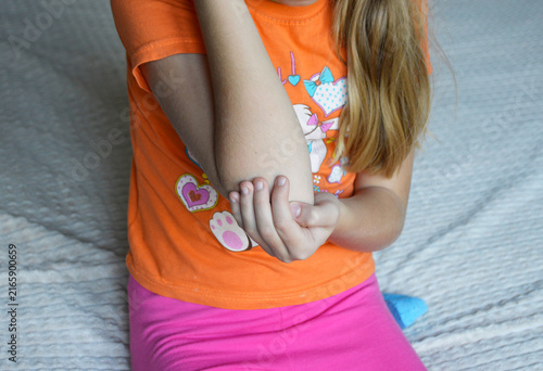A beautiful young woman in casual clothing is holding her elbow. a pained expression is frozen on her face. Her gaze is filled with sadness caused by joint pain, an injury, or some other ailment.