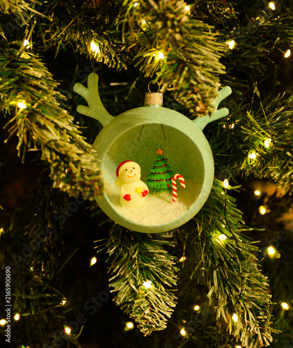 A Christmas tree ornament in the shape of a ball with horns and small figures inside. Decorative gift balls for decorating your home, office, or as gifts. A Christmas tree, Santa Claus, snowman