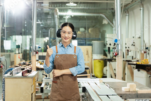 Photography Female carpenter giving thumbs up in woodworking workshop