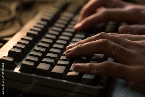 Hands typing on a dark, sleek keyboard.