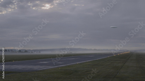 Disc Shaped Flying Saucer UFO Hovering Over Empty Airport Runway in Morning Mist