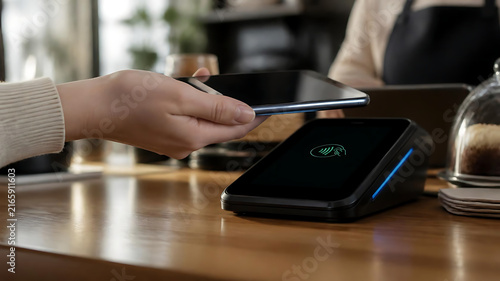 Close-up of a Customer Using a Smartphone for Contactless Payment at a Modern Cafe Counter