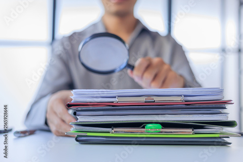 Foto Auditor Using Magnifying Glass Over Stack of Documents to Inspecting or Auditing