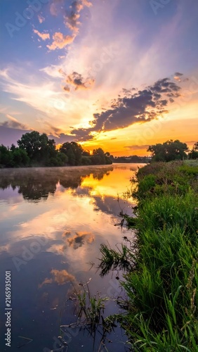 Colorful sunrise reflecting on a calm river surface.