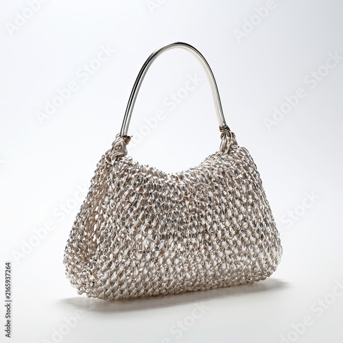 Handmade silver handbag sits on white background.