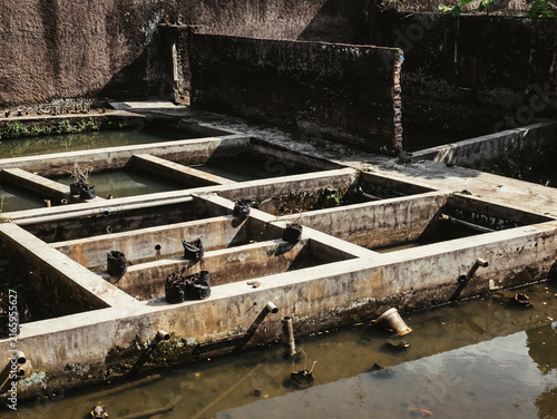 Bild auf Leinwand Neglected concrete fish farm with empty hatchery tanks and murky water