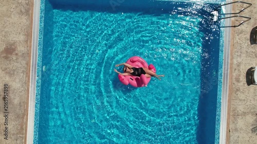 Aerial drone view of woman relaxing on flamingo pool float in pool in hotel. Summer holidays, enjoying summer vacations, luxury hotel
