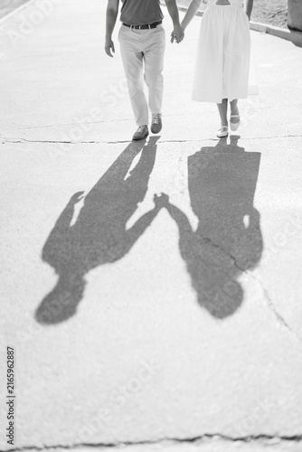 Konstfotografi Black and white couple walking holding hands shadows
