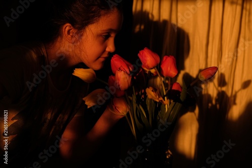 Canvastavla Girl smelling a bouquet of fresh tulips in warm golden hour light