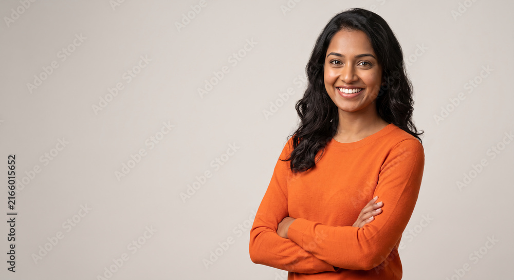 Fototapeta premium Portrait of a confident smiling young professional woman with crossed arms looking at camera standing on grey background with copy space