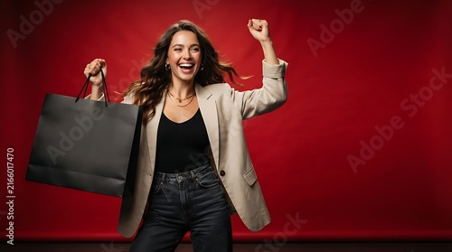 Ecstatic Shopper with Bag: A delighted woman exults, clutching a shopping bag, her raised arm and joyous expression embodying the thrill of retail therapy against a vibrant red backdrop.