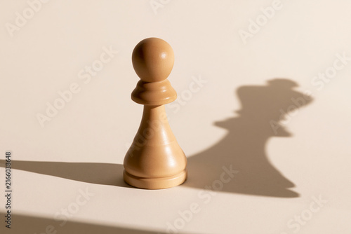 Chess pawn casting a king shaped shadow surreal ambition concept