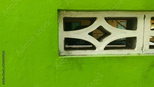 Close-up of a light green painted wall combined with a white concrete ventilation block. Concept of modern architecture, home ventilation, construction materials, and aesthetic background.