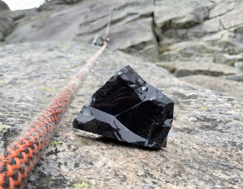 Obsidian Stone Wedged in a Rock Crevice Alongside an Orange Climbing Rope in a Climbing Environment