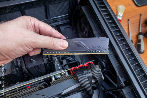 фотографія Technician holding DDR memory module above open case of high-end gaming PC