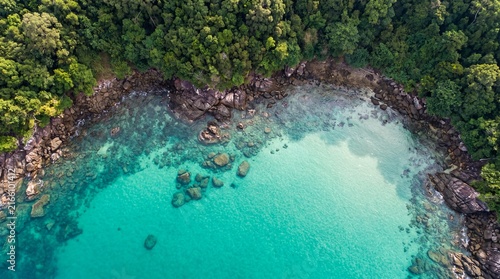 Tropical island aerial view, turquoise ocean water and lush green jungle, rocky coastline of a secluded paradise bay