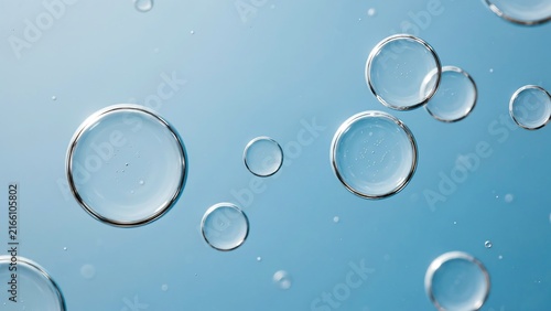 Transparent air bubbles rising inside clean water against soft blue backdrop