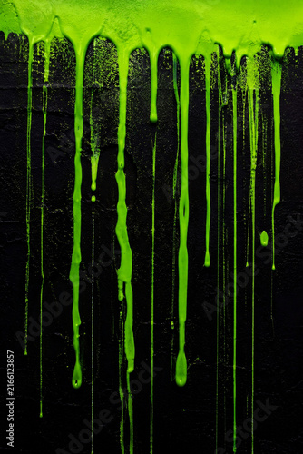 Vibrant Neon Green Paint Dripping Down Dark Textured Wall Background