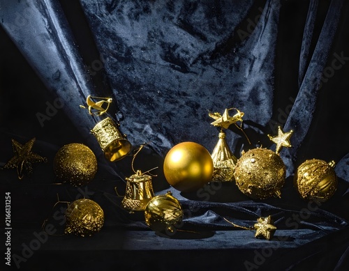 Assorted gold Christmas baubles on navy background.
