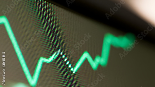 Close-up of digital stock market screen showing dividend stock graph with gre...