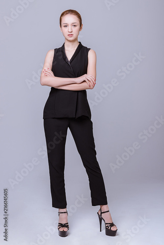 фотографія Confident young woman in black outfit standing with crossed arms