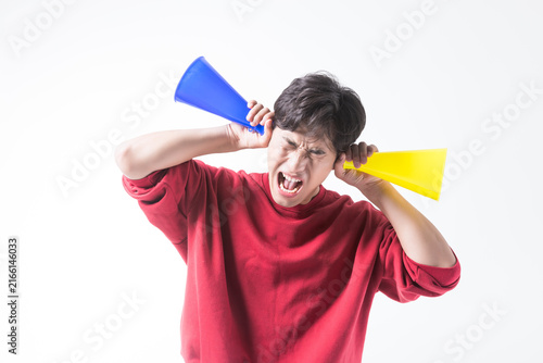 Obraz na plátne Shouting Young Man Covering His Ears with Colorful Cones