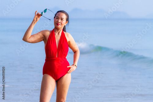Woman with red swimsuit stand happy on beach