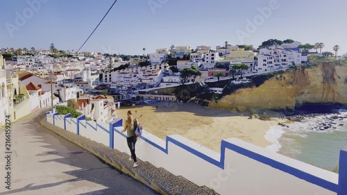 Woman Walking Down Path Overlooking Coastal Town and Beach, Portugal Algarve Travel Concept, Carvoeiro