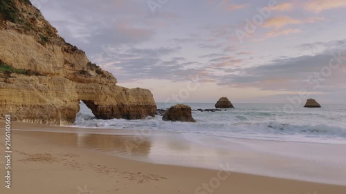 Waves Crashing on Sandy Beach with Rock Formations at Sunset, Coastal Tranquility Concept- Algarve in Portugal
