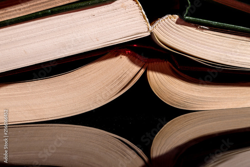 Fotografía Binding of stacked books on a reflective surface, close-up