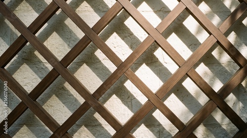 Wooden slats arranged in a diagonal lattice against a textured wall