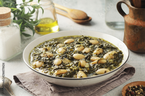 A bowl with traditional Tuscan kale salad and white beans soup Cavolo nero e fagioli