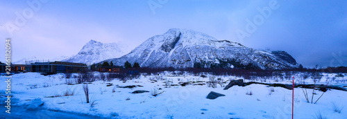 Stunning Wide Panorama of Massive Snow-Covered Arctic Mountains and Winter Landscape at Twilight (Blue Hour) in Norway, with Remote Cabins.