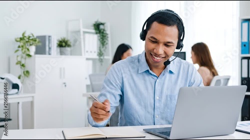Indonesian business man speaking having virtual meeting on laptop. Wearing headset talking consulting on video call at home office call center.