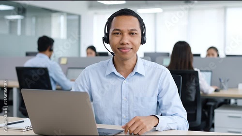 Indonesian business man speaking having virtual meeting on laptop. Wearing headset talking consulting on video call at home office call center.