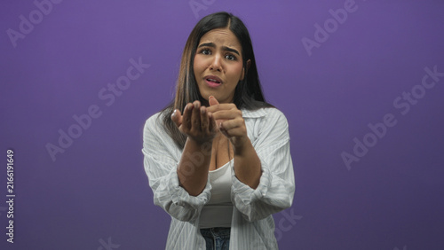 Obraz na płótnie Young hispanic woman holds out cupped hands in a pleading gesture in a studio; desperate vulnerability