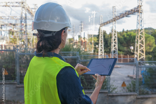 Foto Female engineer in hard hat and safety vest analyzing energy consumption data on