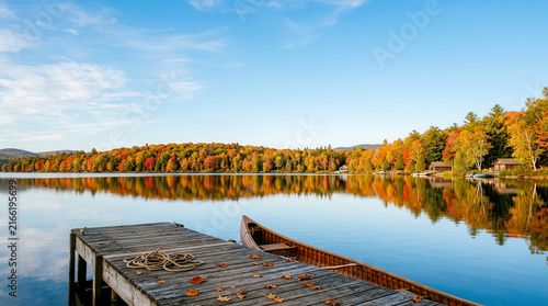 Wooden canoe moored at a wooden dock on a calm lake during autumn season