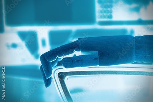Close up of robotic hand resting on office chair with computer workspace in background