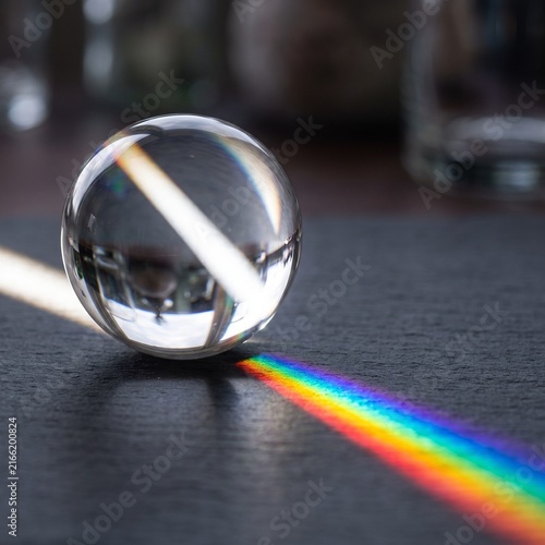 Crystal Sphere Refracting Rainbow Light Across Black Surface
