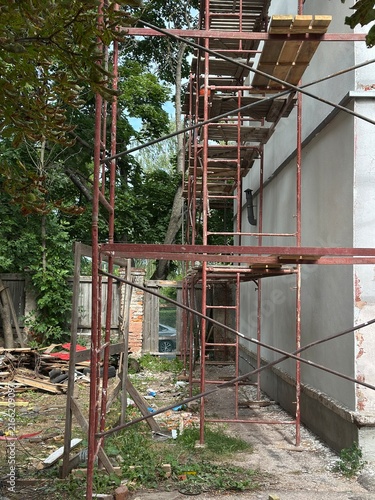 Fotografía Rusty metal scaffolding with wooden planks against a white wall