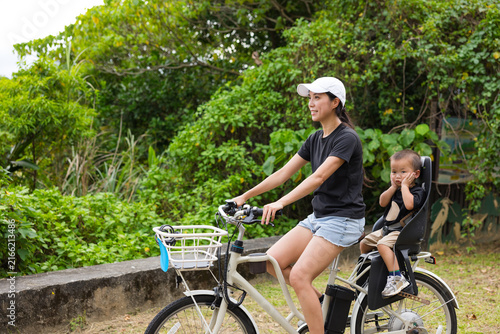 Woman riding bicycle with young child in seat